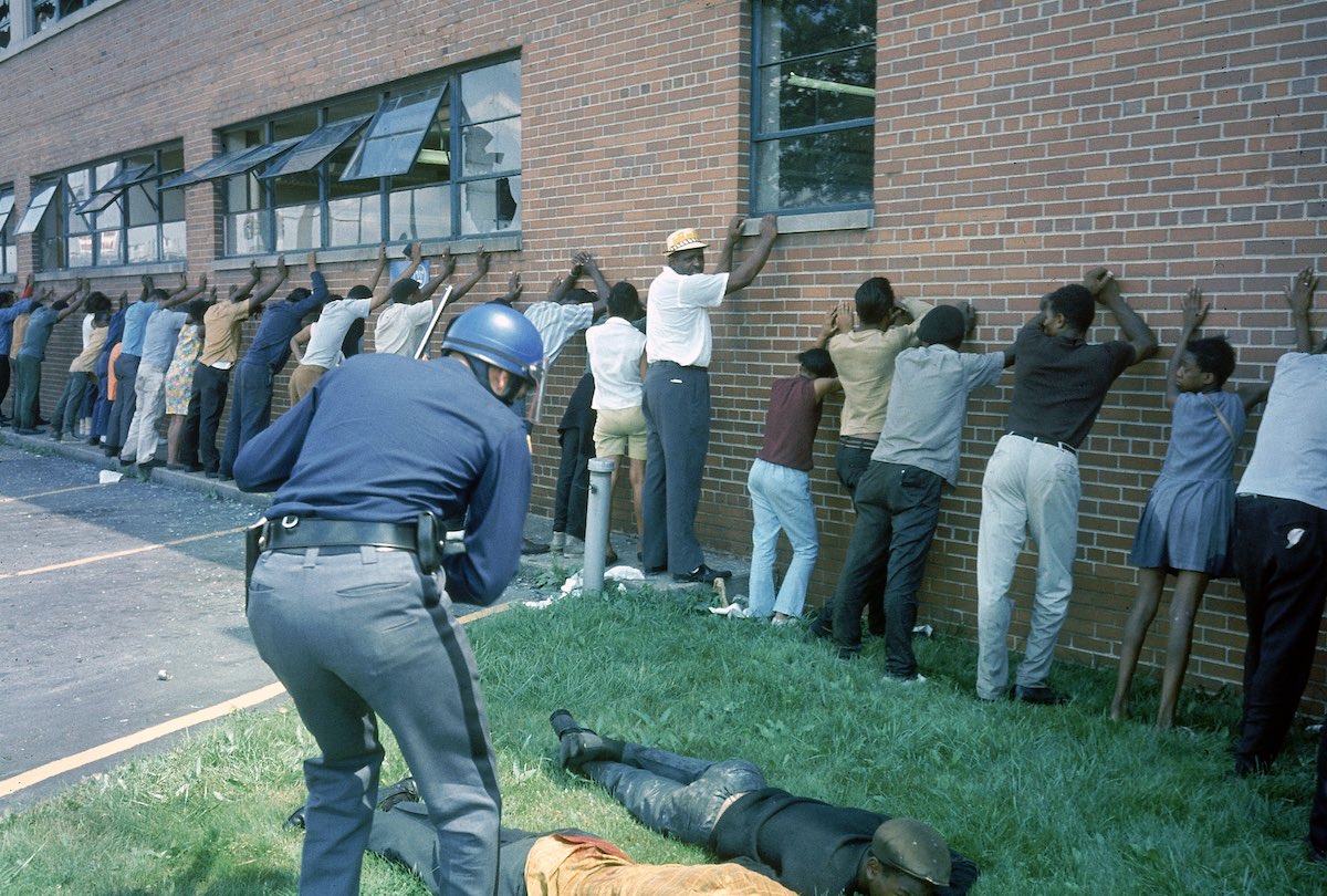Policeman lining up suspects after race riots.