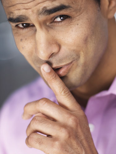 Close-up portrait of a man putting his finger to his lips
