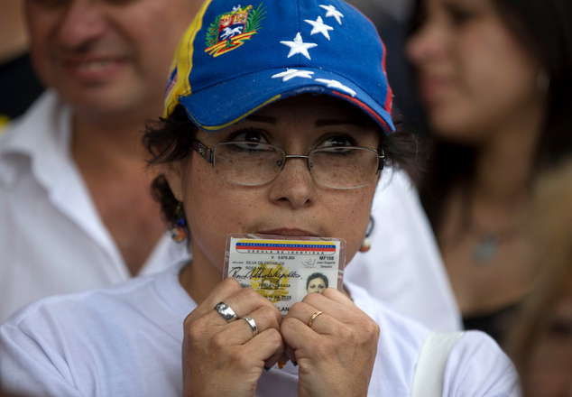 A woman holding her ID cards waits in line to sign a petition to initiate a recall referendum against Venezuela's President Nicolas Maduro in San Cristobal, Venezuela, Wednesday, April 27, 2016. Maduro's approval rating has plummeted amid spiraling triple-digit inflation, a deep recession and widespread shortages. (AP Photo/Fernando Llano)