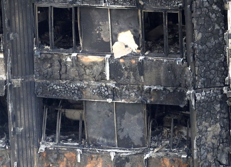 Part of the scorched facade of the Grenfell Tower in London as firefighters continue to damp-down the deadly fire, Thursday, June 15, 2017. A massive fire raced through the 24-storey high-rise apartment building in west London early Wednesday, and London fire commissioner says it will take weeks for the building to be searched and 'cleared'(AP Photo/Frank Augstein)