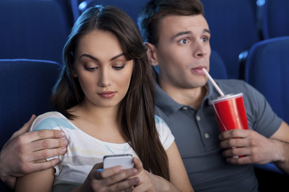 What an exciting movie! Excited young couple eating popcorn and drinking soda while watching movie at the cinema