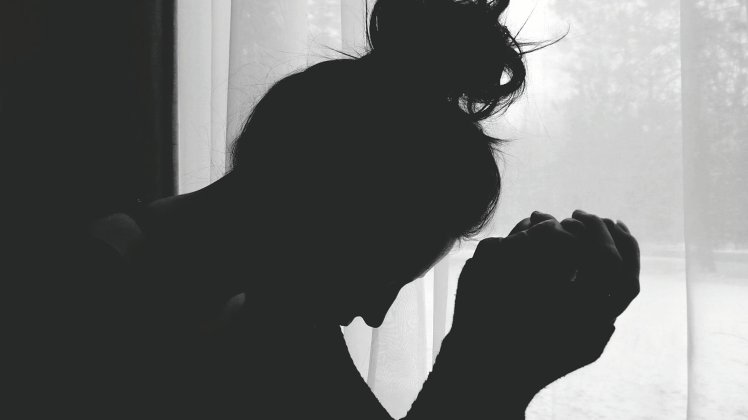Side View Of Silhouette Woman Sitting Against Curtains On Window