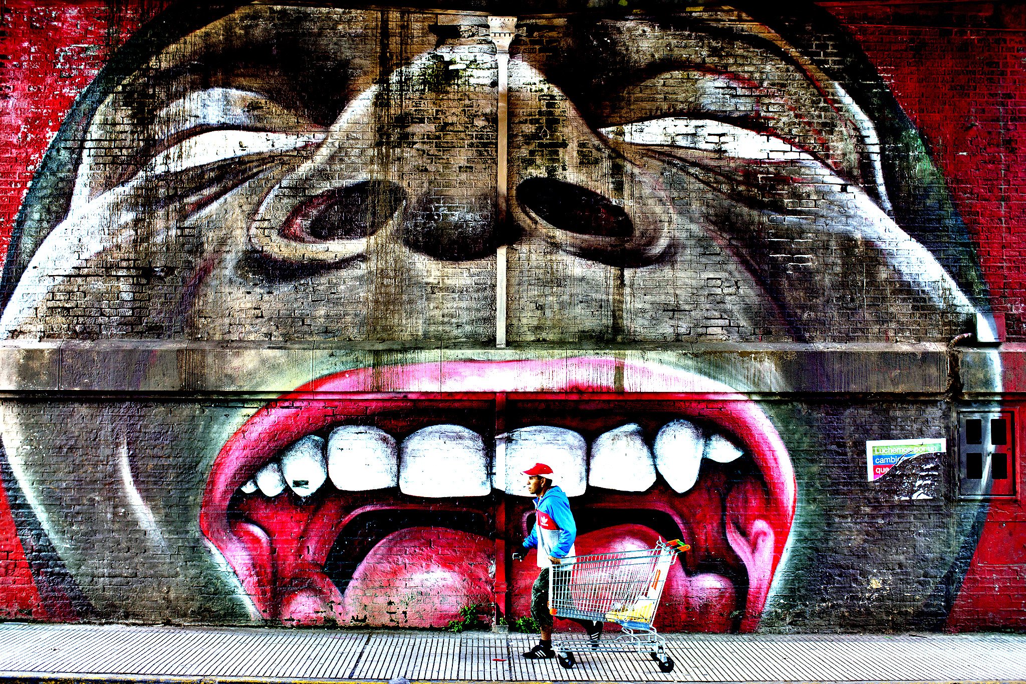 A man with a cart passes in front of a street painting in Buenos