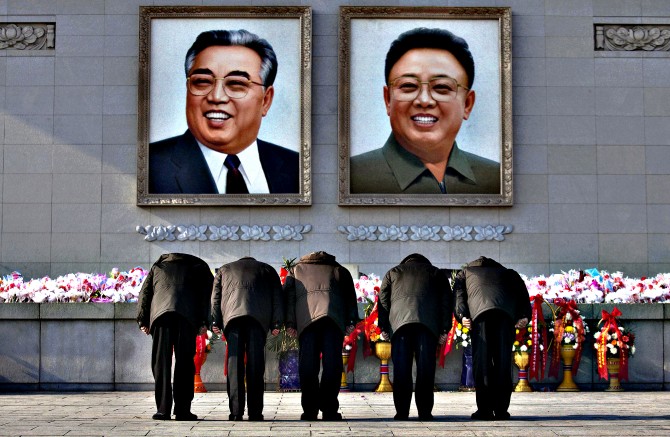 North Koreans bow beneath portraits of the late leaders Kim Jong