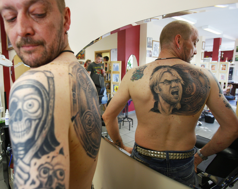 Soccer fan admires his new tattoo of Germany's soccer trophy and Borussia Dortmund coach Klopp at tattoo shop in Unna