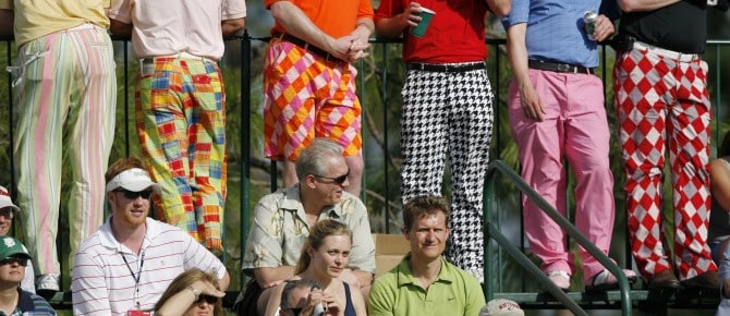 Male spectators wearing colorful retro golf trousers watch from the stands on the 17th hole during third round play at the Arnold Palmer Invitational golf tournament at the Bay Hill Club in Orlando