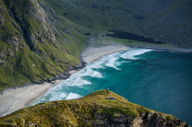 Female hiker overlooking Kvalvika beach from nearby mountain, Moskenesoy, Lofoten Islands, Norway