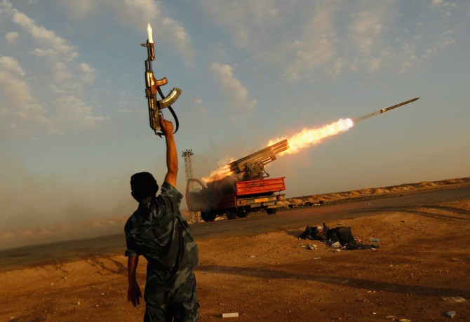 Image: A rebel fighter celebrates as his comrades fire a rocket barrage toward the positions of troops loyal to Libyan ruler Muammar Gaddafi
