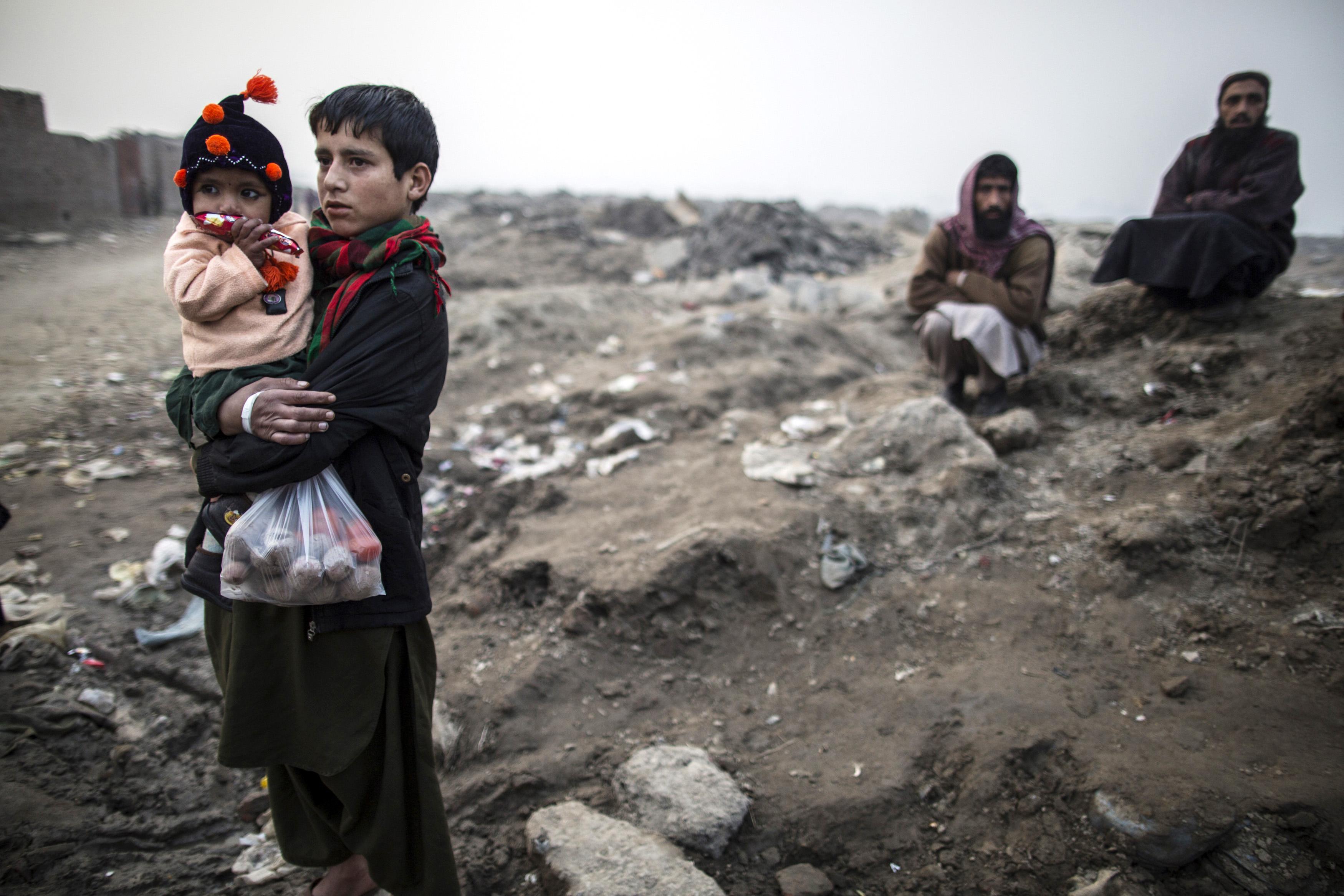 A teenage boy carries his sibling in a slum on the outskirts of Lahore