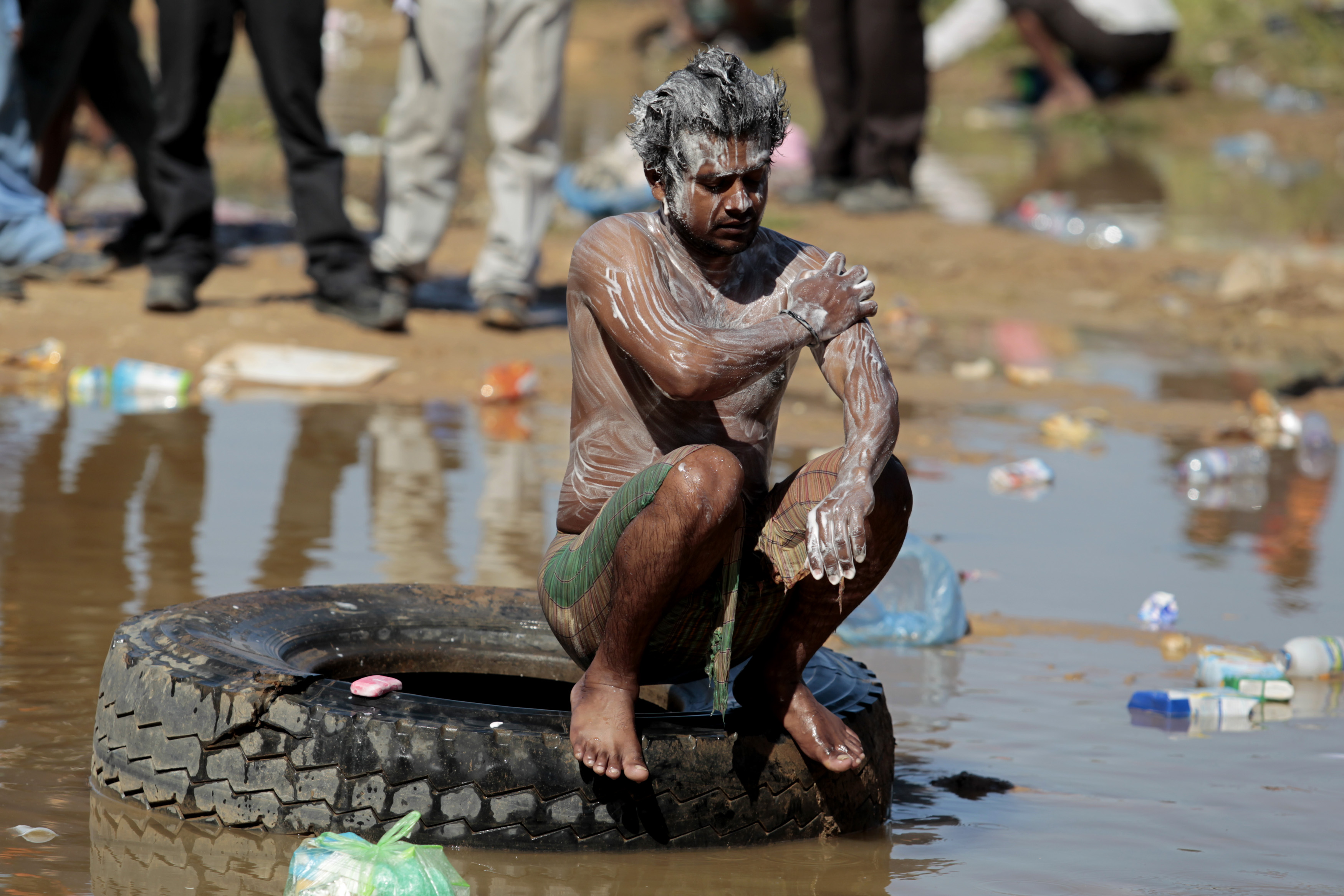 A Bangladeshi migrant worker washes himself in a puddle of water at the Libyan and Tunisian border crossing of Ras Jdir after fleeing unrest in Libya