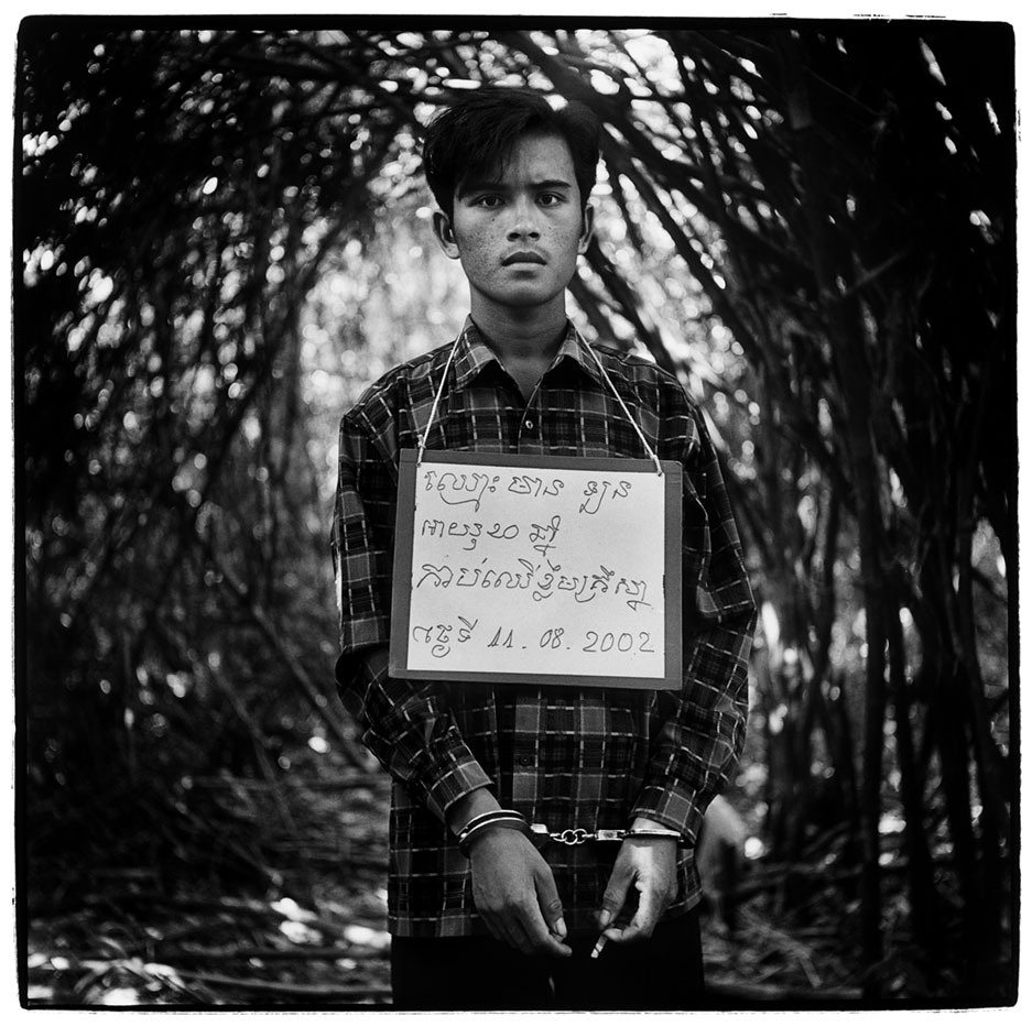 Cambodia, BokorA handcuffed poacher is photographed with a notice bearing details of his name, age and the nature and date of his crime. While operating as part of a poaching team in Bokor National park he was brought for questioning by members of the National Cambodian Forestry Security service. Cambodia 2002