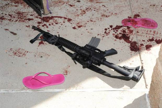 This July 2012 evidence photo, which the Arapahoe County District Attorney's Office released in response to open-records requests, shows an assault weapon and blood by sandals following the July 20, Colorado theater shooting by James Holmes in Aurora, Colo. In August 2015, Holmes was sentenced to life in prison because jurors could not agree that he deserved the death penalty. (Arapahoe County District Attorney's Office via AP)