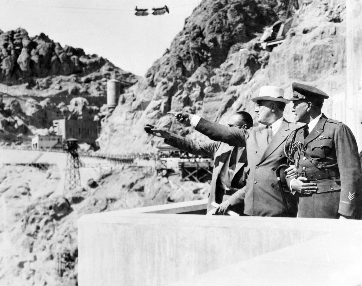 ca. 1935 --- Original caption: President Roosevelt, high up on one side of the huge Boulder Dam at Boulder City, Nevada, points to one feature of the mighty structure, and asks a question. Walker Young, the engineer in charge of the project conducted the Chief Executive on a tour of the dam, after which Roosevelt made a dedication address, during which he pointed out that federal spending had given the nation useful works such as this one, and had started the wheels of private industry turning. --- Image by © Bettmann/CORBIS