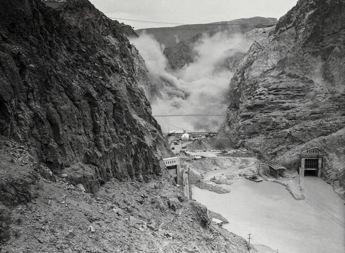 12 May 1933, USA --- Original caption: Near Las Vegas: 4-Ton Dynamite Blast Set Off At Hoover Dam Site. A mountain of dirt and rock rises skyward after a four ton dynamite blast was set off, marking the last "big shot" before construction of Hoover Dam proper begins near Las Vegas, Nevada. The explosives were detonated from 3,000 drill holes honeycombing the section of earth to be moved, a rock ledge on the lower canyon walls selected as the site for power houses. The roar of the explosion echoed through the walls of Black Canyon for 15 minutes. --- Image by © Bettmann/CORBIS