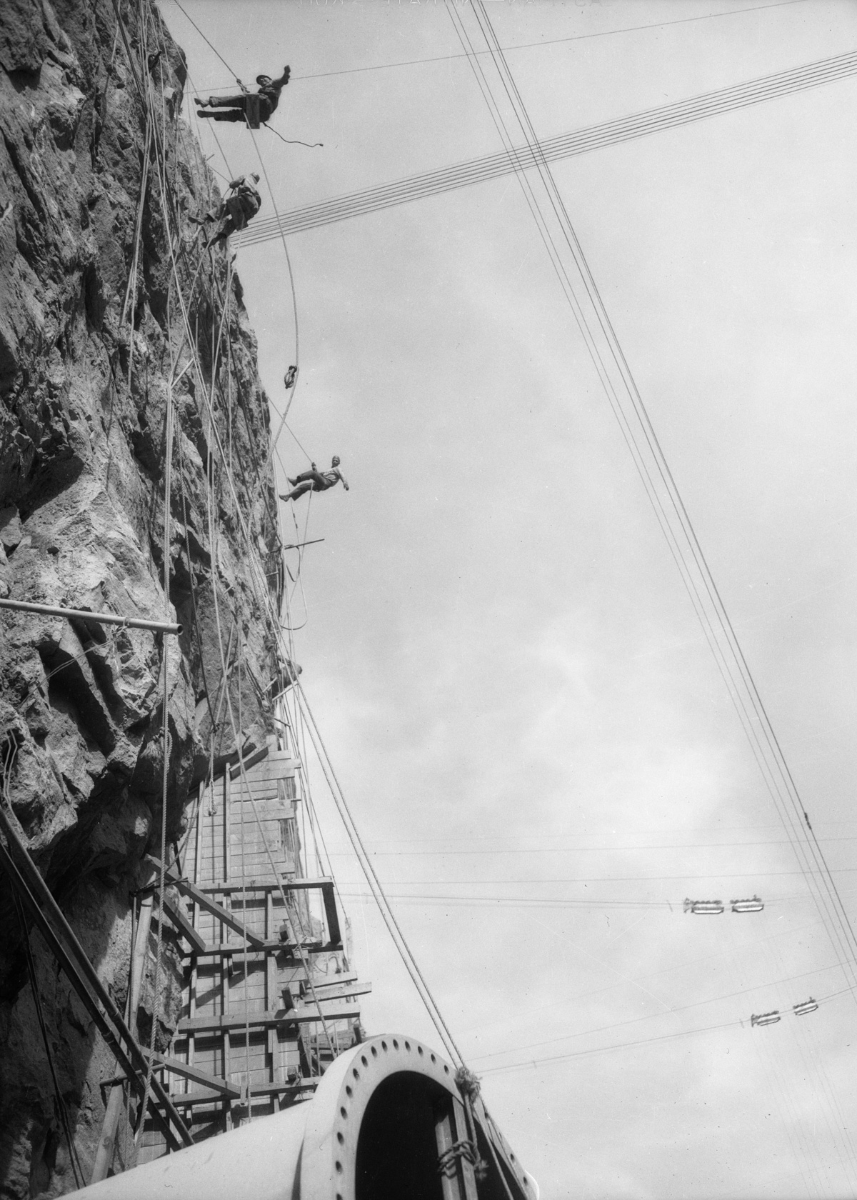 1934 --- Contruction workers rappel down cliff face dw-1934-12-08-70~09 --- Image by © Dick Whittington Studio/Corbis