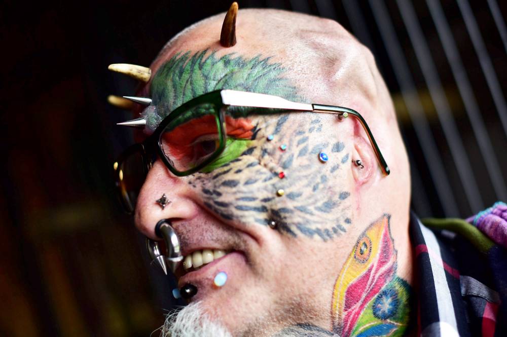 Extreme body mod fan Ted Richards, AKA Parrot man - who has had his ears cut off to look like his parrot. See SWNS story SWPARROT; A man who had his face and eyeballs tattooed to look like his pet parrots has gone a step further - by cutting off his EARS. Bonkers Ted Richards, 56, is obsessed by pets Ellie, Teaka, Timneh, Jake and Bubi and has his face tattooed with colourful feathers. But the animal nut - who has 110 tattoos, 50 piercings and a split tongue - has now had both his ears removed by a surgeon in a six hour operation. Eccentric Ted has given his severed ears to a friend who "will appreciate them" and is now planning to find a surgeon prepared to turn his nose into a BEAK.