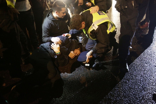 A photographer lays on the floor, after being hit by an Aston Martin which was surrounded by protestors in Lower Grosvenor Place, near Victoria in London, during the Million Mask March bonfire night protest organised by activist group Anonymous.