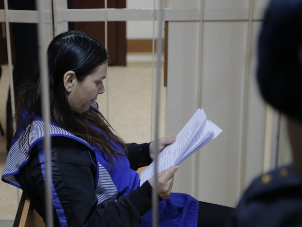 epa05190009 Gyulchehra Bobokulova behind cage bars reading papers during a court hearing at the Presnensky district court in Moscow, Russia, 02 March 2016. Gyulchehra Bobokulova from Uzbekistan was arrested 29 February 2016 near the Oktyabrskoye Pole underground station where she had appeared dressed in black and carrying a severed child's head and shouting. Bobokulova was the baby's nanny. EPA/MAXIM SHIPENKOV / POOL
