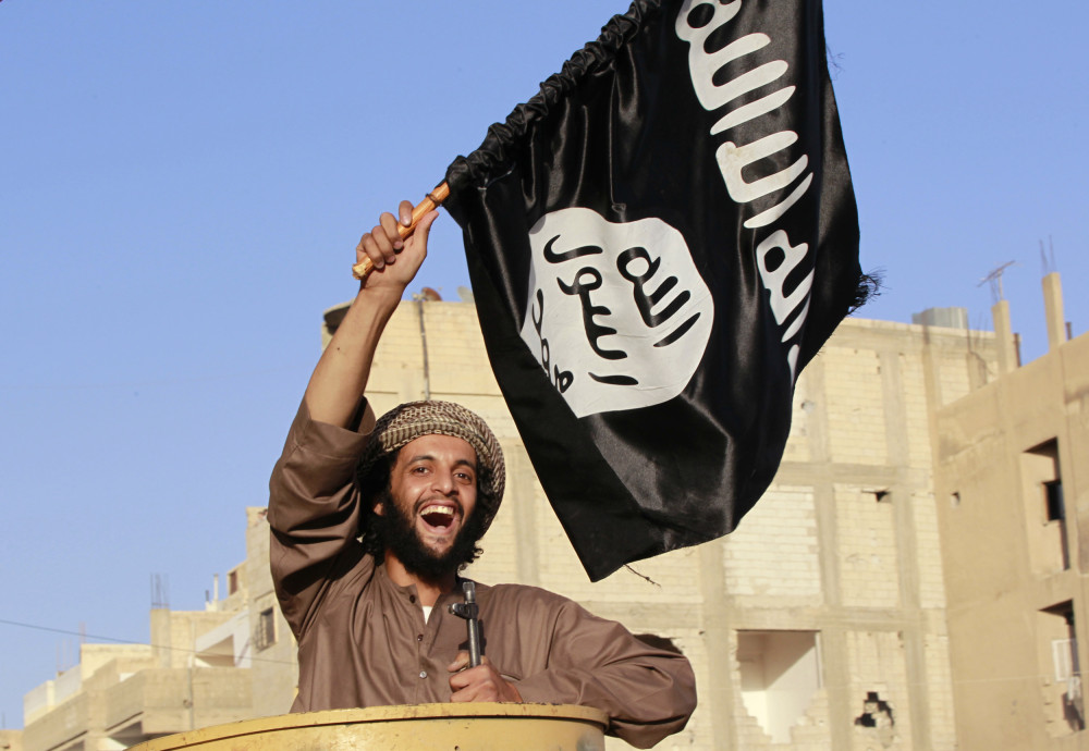 Militant Islamist fighter waving a flag, cheers as he takes part in a military parade along the streets of Syria's northern Raqqa province