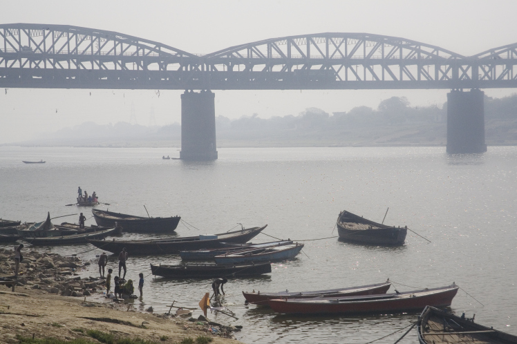 Ganges river shore wooden boats and iron bridge