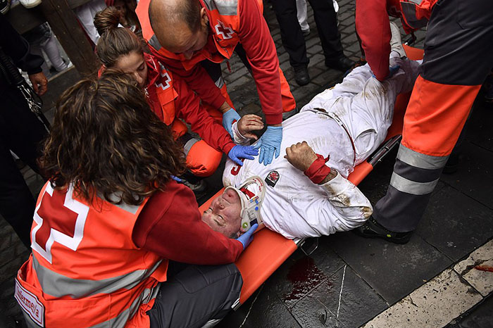 A injured reveler is tended to by medics on the Estafeta corner during seventh running of the bulls with Nunez del Cubillo's ranch bulls at the San Fermin Festival, in Pamplona, northern Spain, Wednesday, July 13, 2016. Revelers from around the world flock to Pamplona every year to take part in the eight days of the running of the bulls. (AP Photo/Alvaro Barrientos)