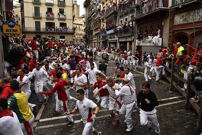 Revelers run around Nunez del Cubillo's fighting bulls on the Estafeta corner during the seventh running of the bulls at the San Fermin Festival, in Pamplona, northern Spain, Wednesday, July 13, 2016. Revelers from around the world flock to Pamplona every year to take part in the eight days of the running of the bulls. (AP Photo/Alvaro Barrientos)