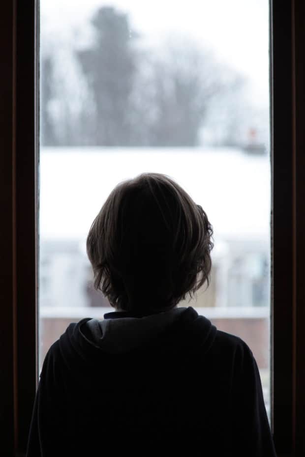 A boy looking at snow through a window, UK