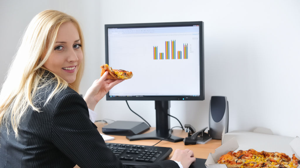 Woman eating pizza at work