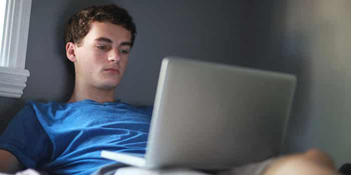 Teenage boy in room using laptop