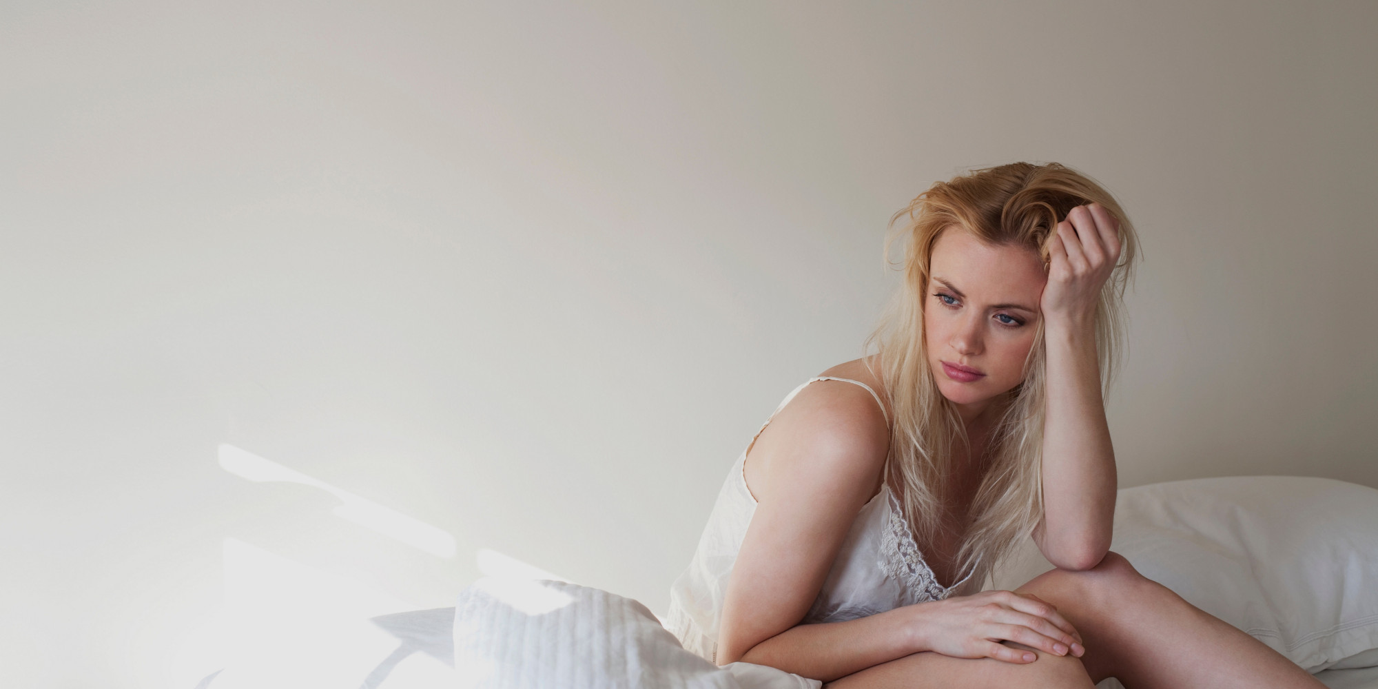 Upset young woman sitting on bed