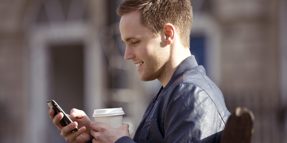 A young man sitting on a bench, using his mobile phone