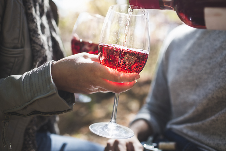 Cropped close up of couple pouring rose wine in forest