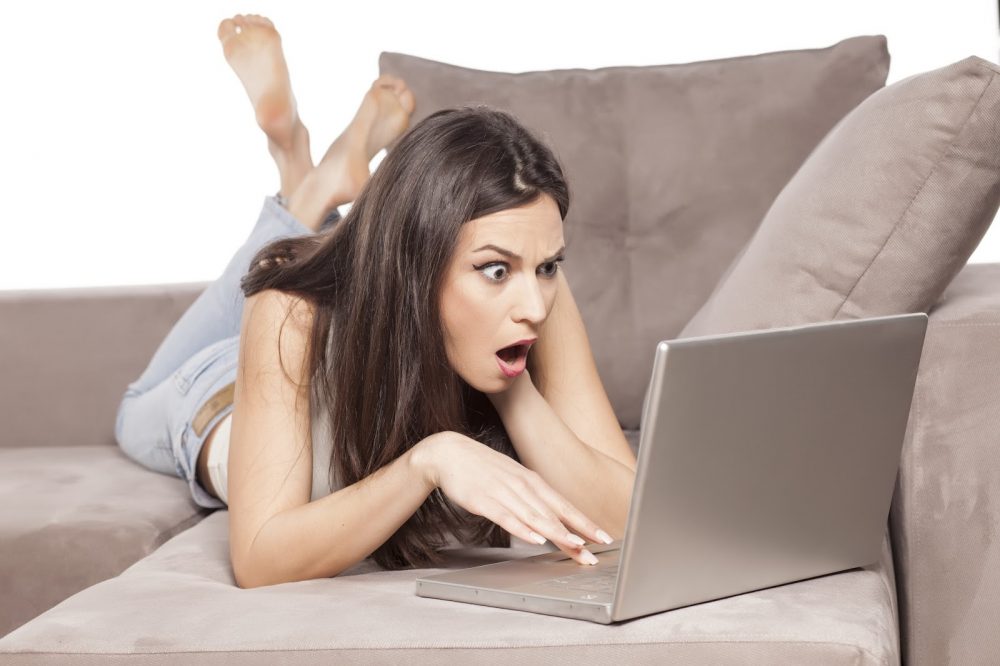shocked girls looking at laptop on couch