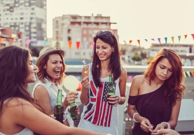 Girls with beer bottles and sparklers partying on the rooftop