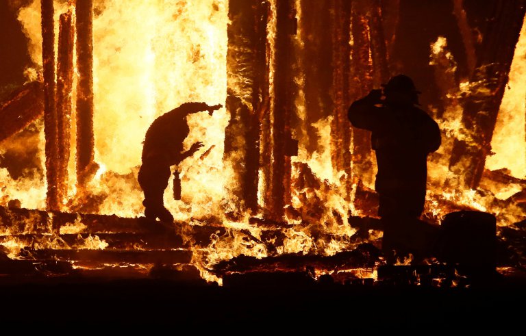 Burning Man participant runs into the flames of the "Man Burn" at the Burning Man arts and music festival in the Black Rock Desert of Nevada