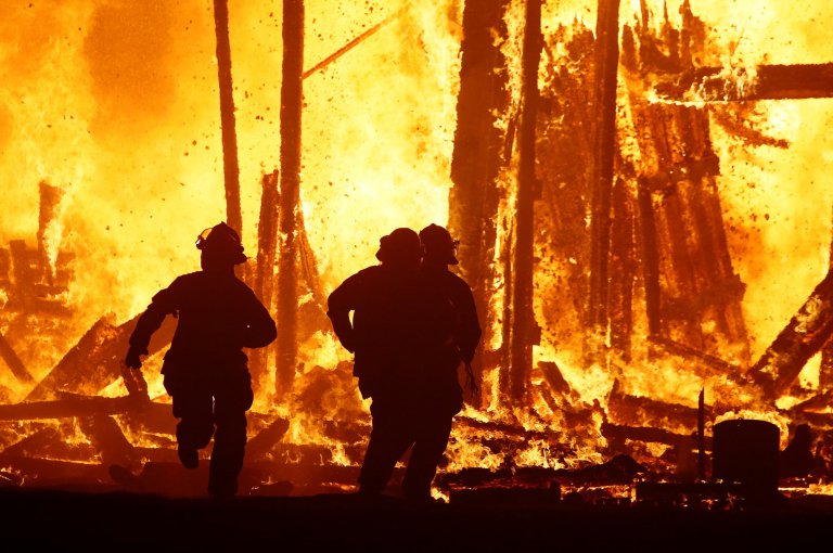 Firefighters flee collapsing structure after a Burning Man participant runs into the flames of the "Man Burn" at the Burning Man arts and music festival in the Black Rock Desert of Nevada