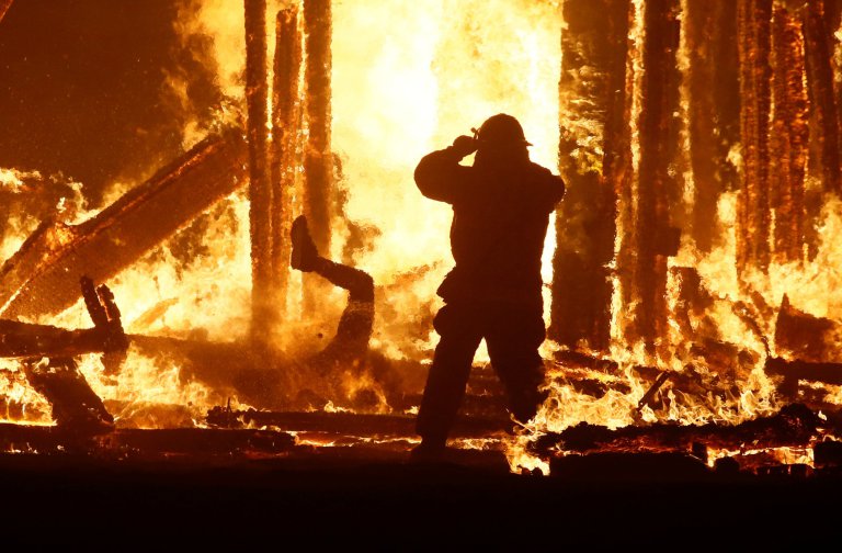 Burning Man participant runs into the flames of the "Man Burn" at the Burning Man arts and music festival in the Black Rock Desert of Nevada