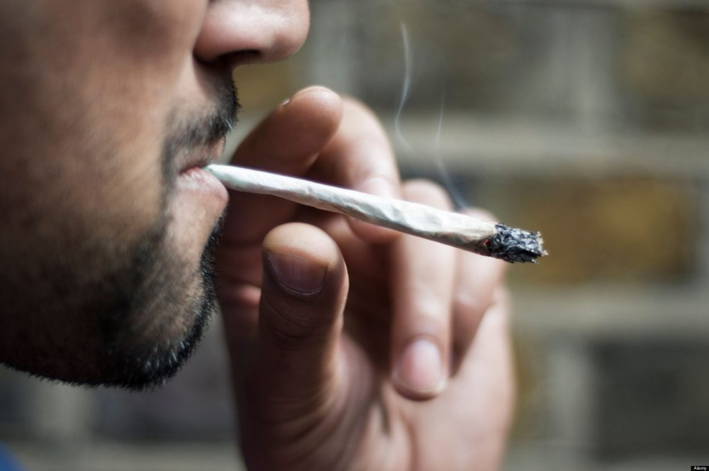 Close-up of an Asian man smoking marijuana joint