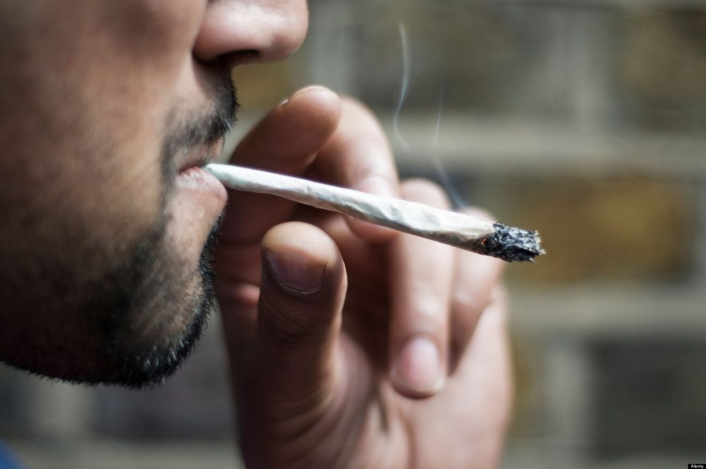 Close-up of an Asian man smoking marijuana joint