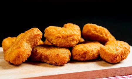 Close-Up Of Chicken Nuggets On Cutting Board Against Black Background