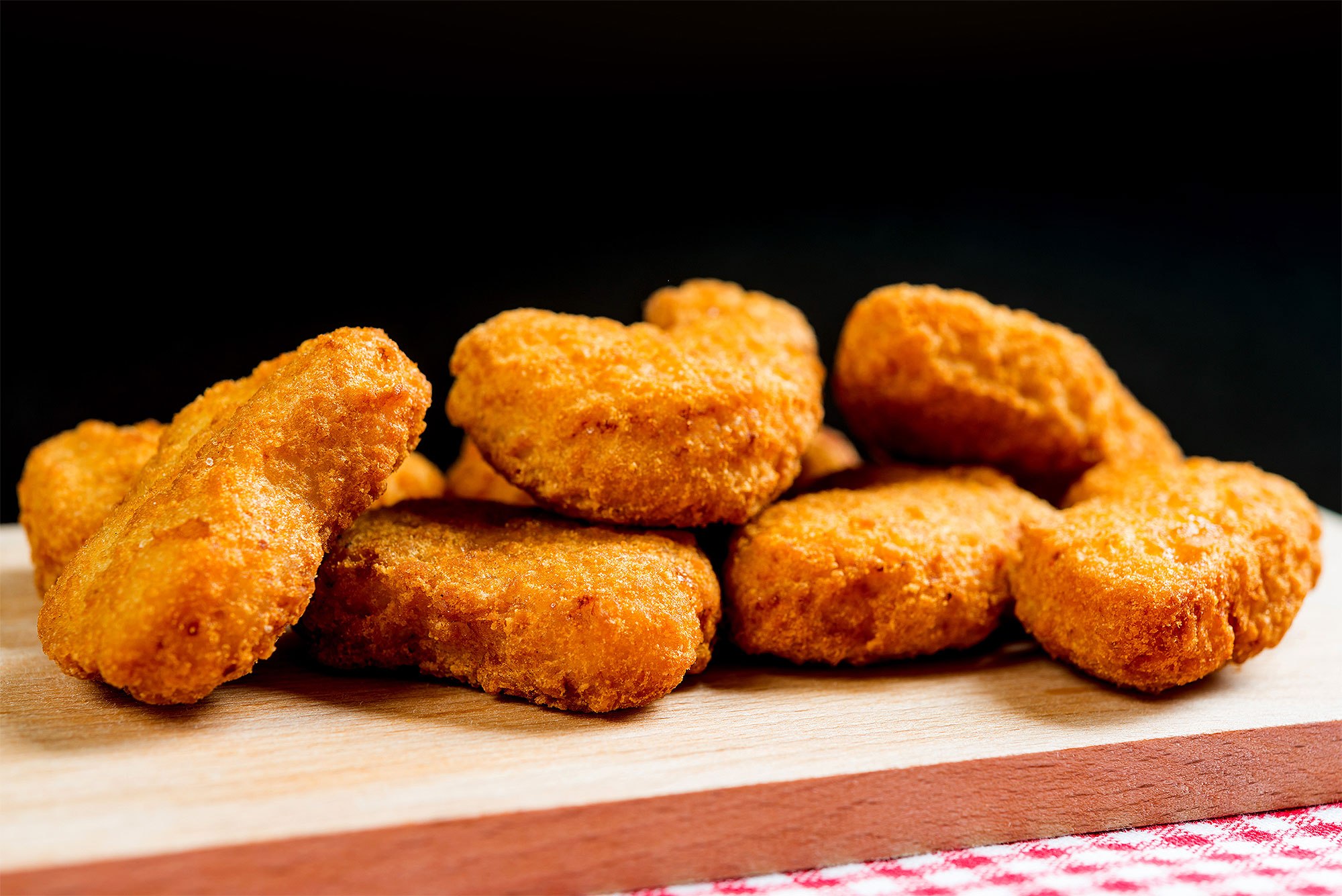 Close-Up Of Chicken Nuggets On Cutting Board Against Black Background